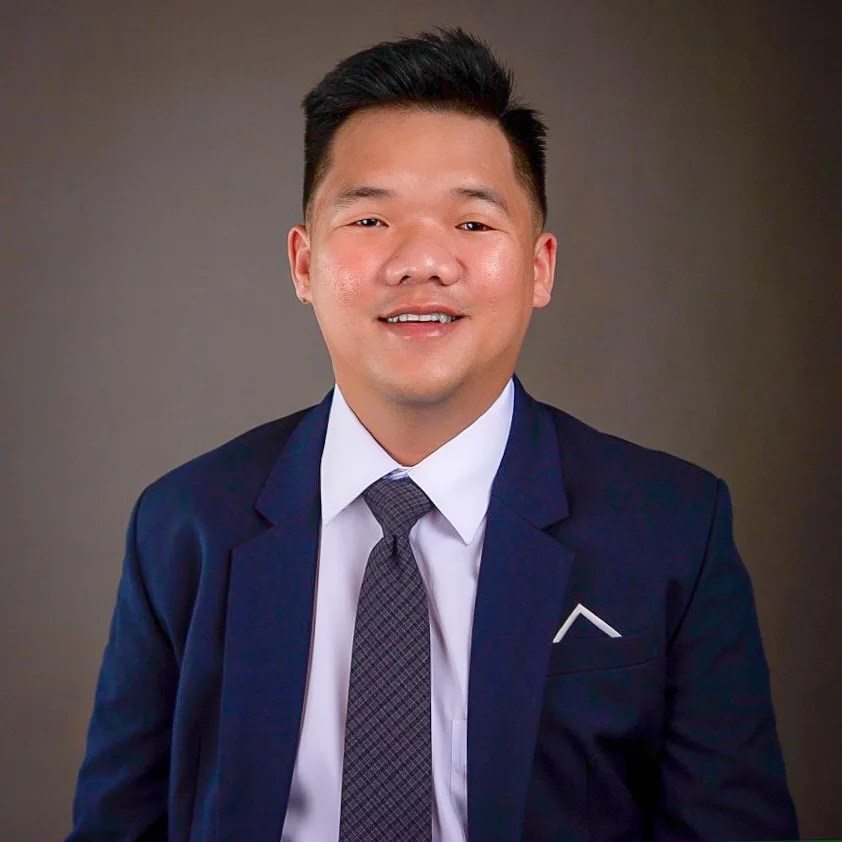 Le Pham in a navy suit, smiling at the camera
