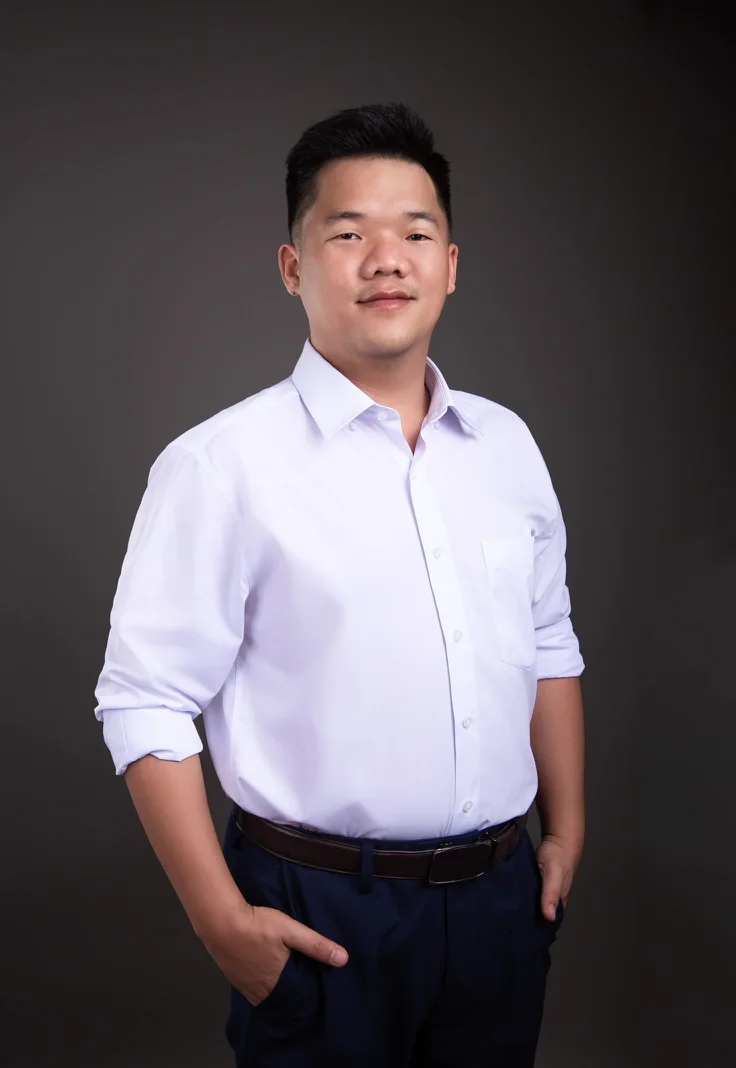 Le Pham in a white shirt, sleeves rolled up, one hand in his pocket, smiling