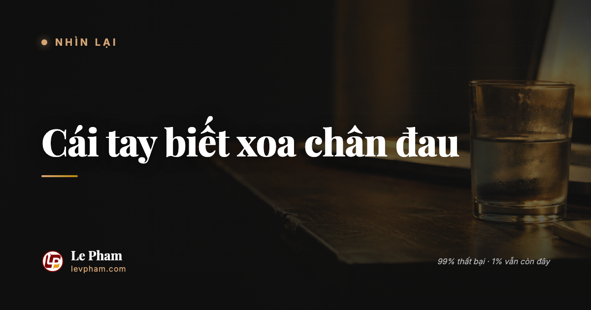 Người đàn ông Việt ngồi cạnh chiếc bàn buổi tối, tay xoa chân vừa va vào cạnh bàn, ly nước nguội đặt bên cạnh.